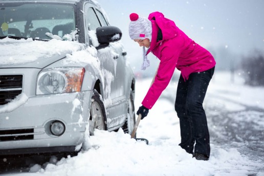 woman shoveling snow from her car